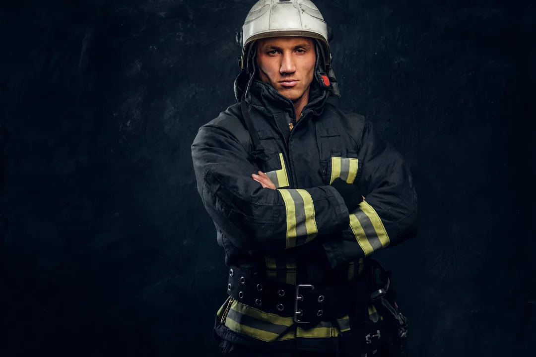 brutal-fireman-uniform-posing-camera-standing-with-crossed-arms-confident-look-studio-photo-against-dark-textured-wall-scaled-1.webp
